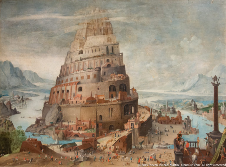 Huge multi-tiered tower dominates a painted waterside city of roads, buildings, tiny figures, and a tall column.