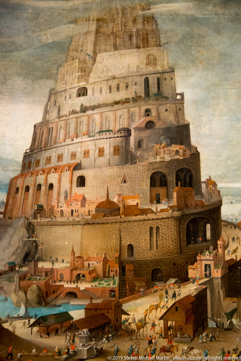 Huge terraced tower with arcades and ramps rises above a busy painted city filled with tiny workers.