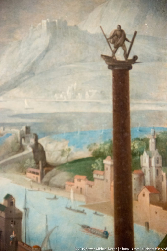 Tall column topped by a figure above a painted harbor city with walls, waterways, mountains, and small boats.