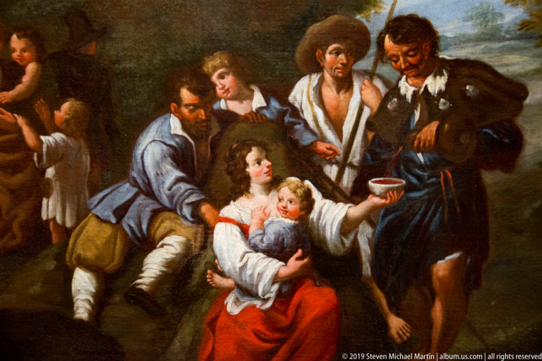 Painted travelers gathered around a seated woman with children; men carry staffs, packs, and a cup.
