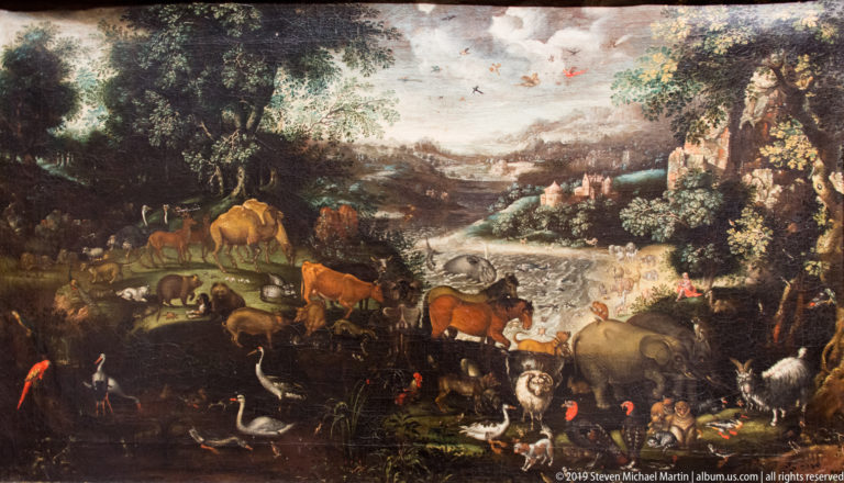 Dark landscape painting crowded with cattle, sheep, goats, birds, and other animals beside water and wooded cliffs.