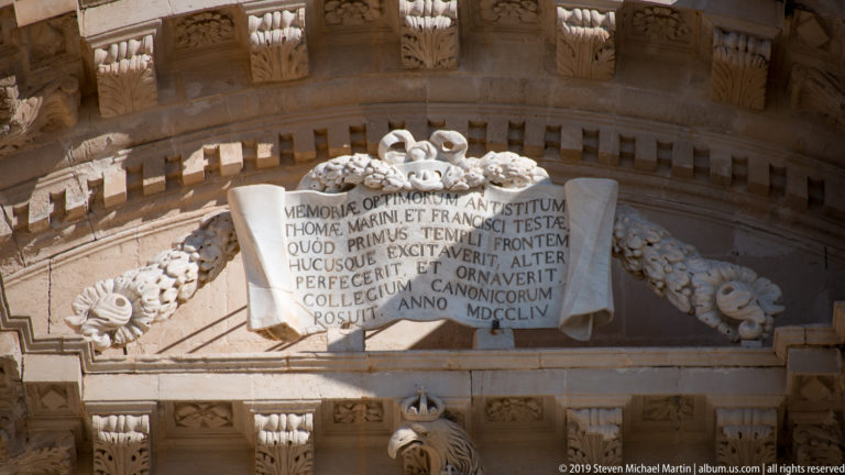 Latin inscription dated MDCCLIV on a scroll-shaped stone panel surrounded by floral swags and carved moldings.
