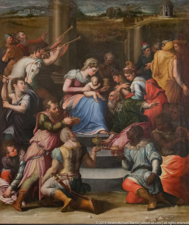Large Renaissance painting with the Virgin and Child at center, surrounded by kneeling and standing figures in colorful robes.