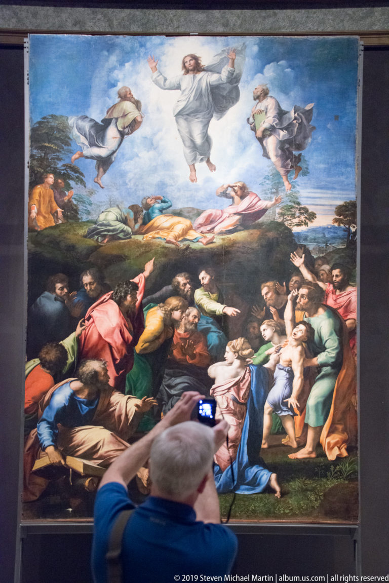 Raphael's Transfiguration with Christ floating above the apostles while a crowded group gathers around a distressed boy below.