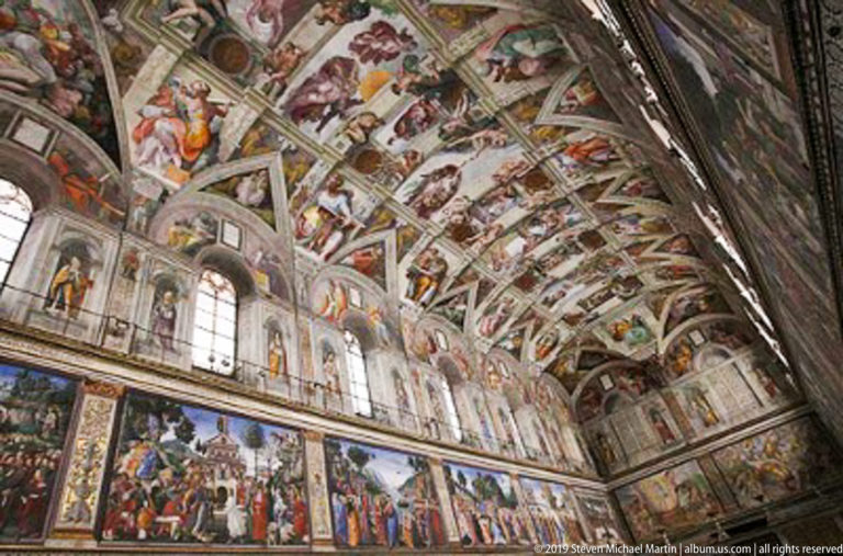 Oblique interior view of the Sistine Chapel with Michelangelo's painted vault above windows and large frescoes along the walls.