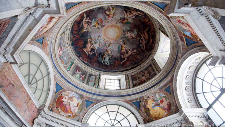 Circular frescoed cupola with a bright central disk, swirling figures, surrounding windows, and painted roundels below.