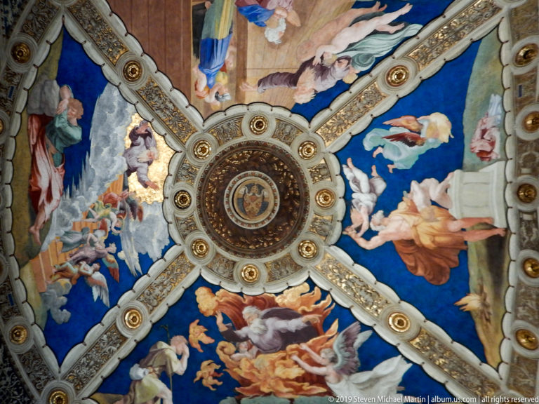 Four-part Renaissance vault with vivid blue narrative frescoes, a circular central medallion, and ornate gilded ribs.