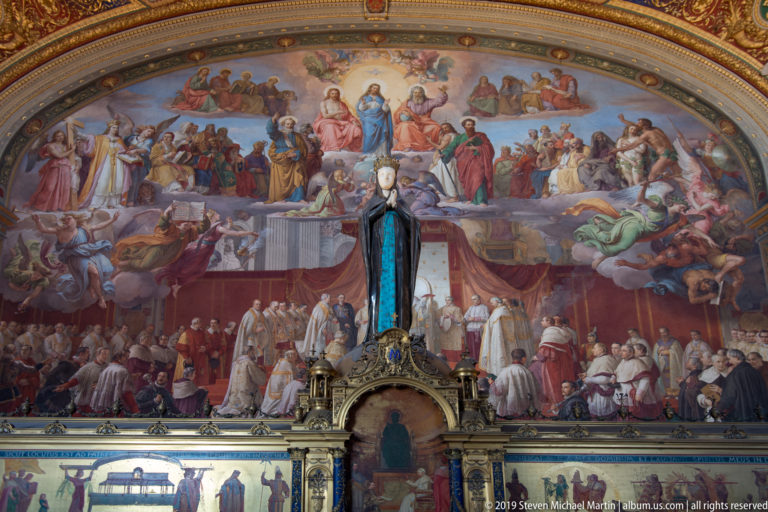 Large papal ceremonial fresco with clergy and dignitaries below a heavenly assembly, partly obscured by a dark devotional statue.