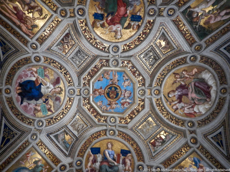 Geometric Renaissance ceiling with four circular figure frescoes, triangular panels, gilded ribs, and a blue central medallion.