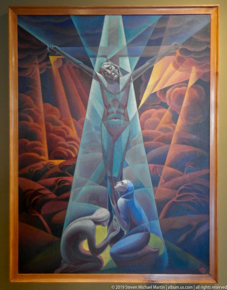 Modernist painting of Christ on the cross rendered in angular blue and green planes, with a kneeling figure below and red clouds behind.