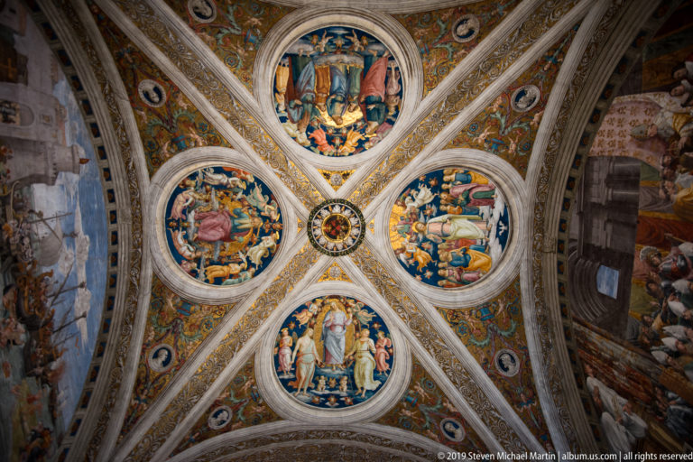 Cross-vault with four large circular narrative paintings around a central medallion, framed by pale ribs and dense Renaissance ornament.