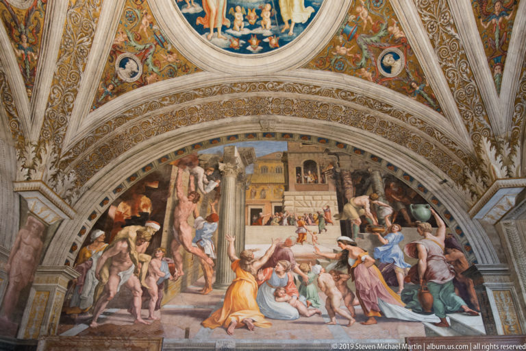Large arched Renaissance fresco crowded with figures beneath an ornate painted and gilded vault.