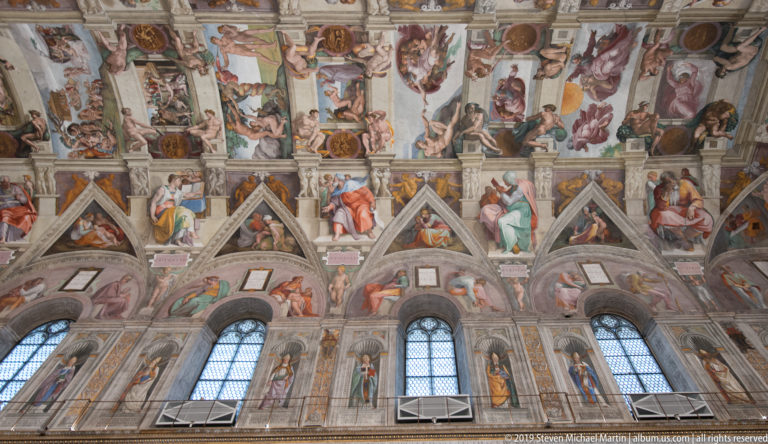 Three tall Sistine Chapel windows beneath frescoed lunettes, painted figures, and Michelangelo's decorated ceiling.