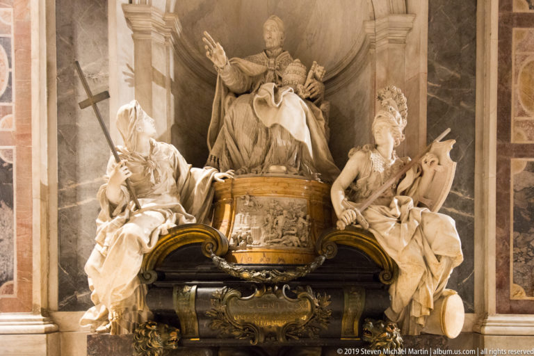 Elaborate papal tomb with seated pontiff above a central base and large marble allegorical figures on both sides.