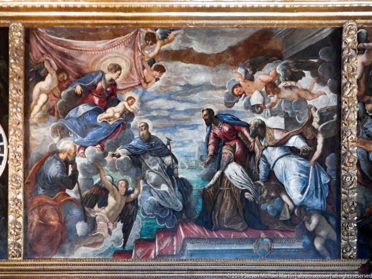 Large religious painting with angels and robed figures set in clouds, enclosed by an ornate gilded architectural frame.