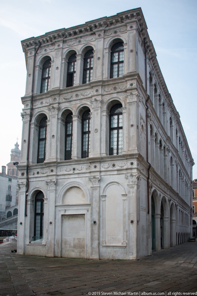 Pale three-story market building with rows of arched windows and a ground-floor arcade in the Rialto district.