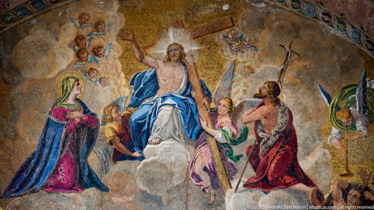 Gold mosaic with a central Christ figure in blue and white surrounded by kneeling and standing figures.