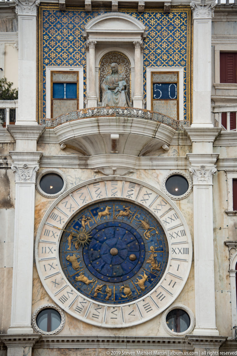 Astronomical clock below a Madonna and Child niche and blue numeral panels on St. Mark’s Clock Tower.