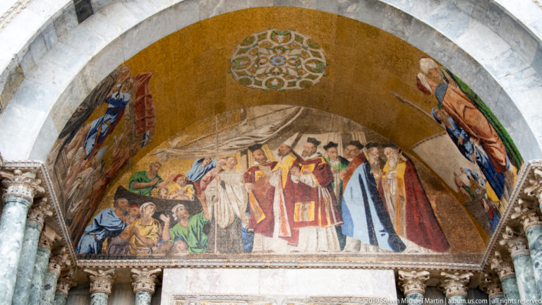 Gold mosaic lunette showing a ceremonial procession of robed figures beneath a marble arch.