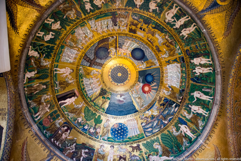 Circular Genesis mosaic dome with concentric narrative scenes, green outer fields, gold inscriptions, and bright central medallion.