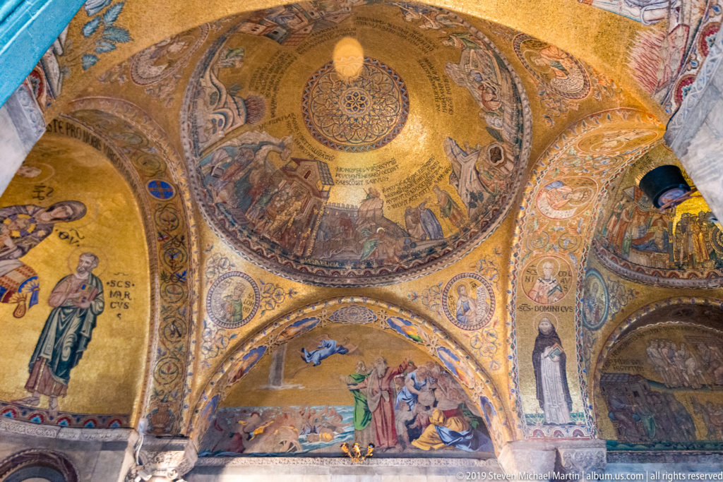 Gold mosaics with saints and narrative scenes covering intersecting domes, pendentives, and arches inside St. Mark’s Basilica.