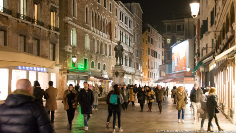 Busy pedestrian shopping street in central Venice under nighttime illumination in Venice.