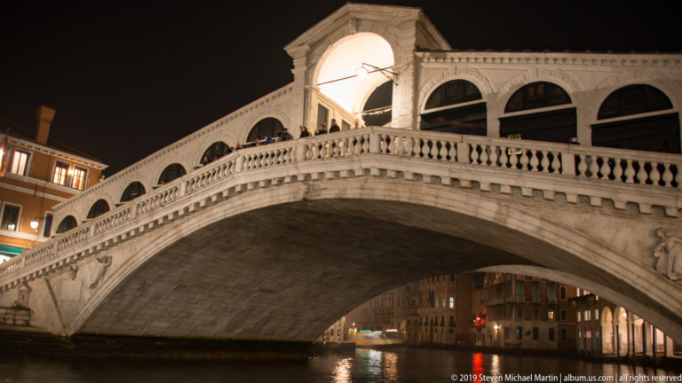Rialto Bridge in close side view under nighttime illumination in Venice.