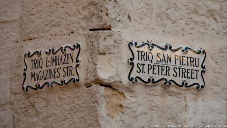 Decorative ceramic signs for Triq L-Imħażen and Triq San Pietru mounted on a weathered limestone corner.