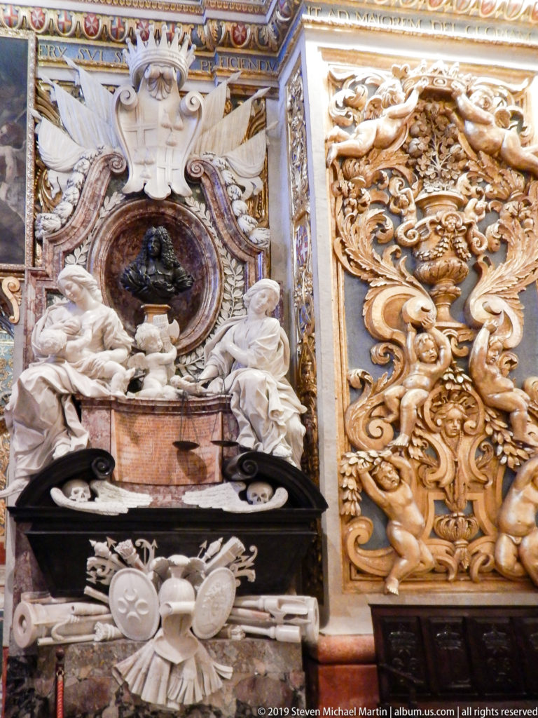 Ornate wall monument with pale reclining figures, colored marble, heraldic motifs, and adjacent gilded relief.