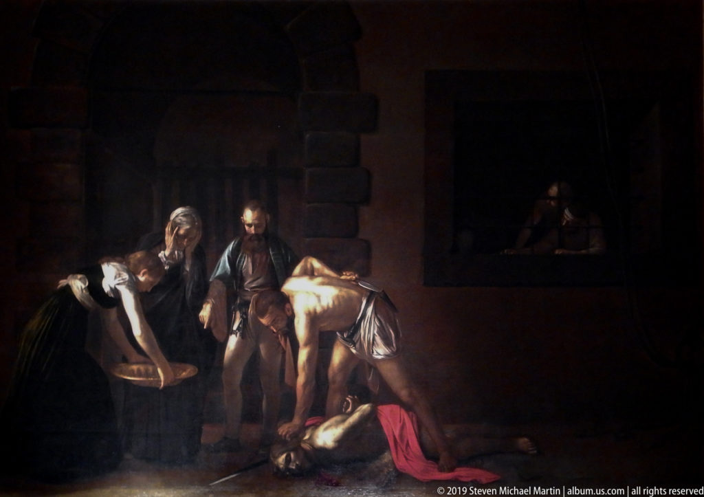 Caravaggio’s dark prison scene shows an executioner over the fallen Saint John the Baptist while nearby figures witness the killing.