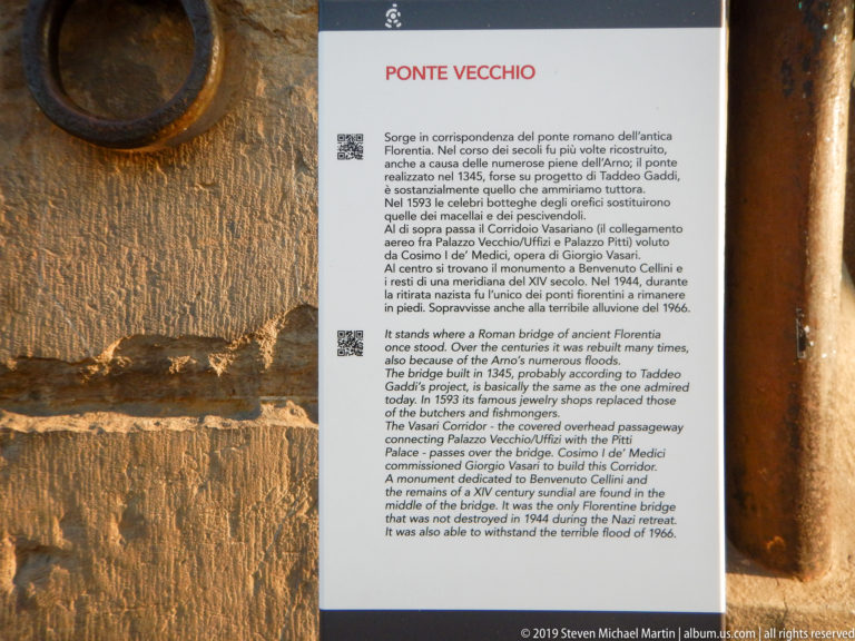 Bilingual Italian-English Ponte Vecchio information panel with historical text and two QR codes mounted on a rough stone wall.