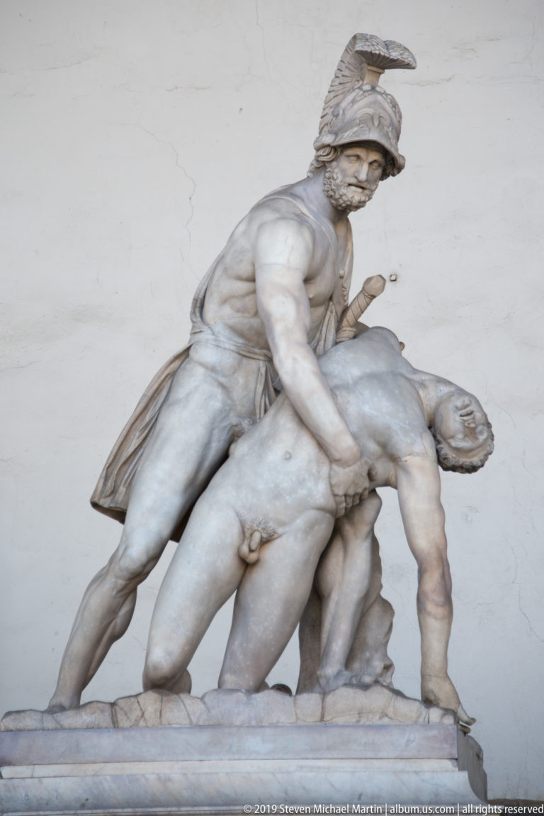Helmeted marble warrior supporting the limp body of a fallen nude man beneath the Loggia dei Lanzi.