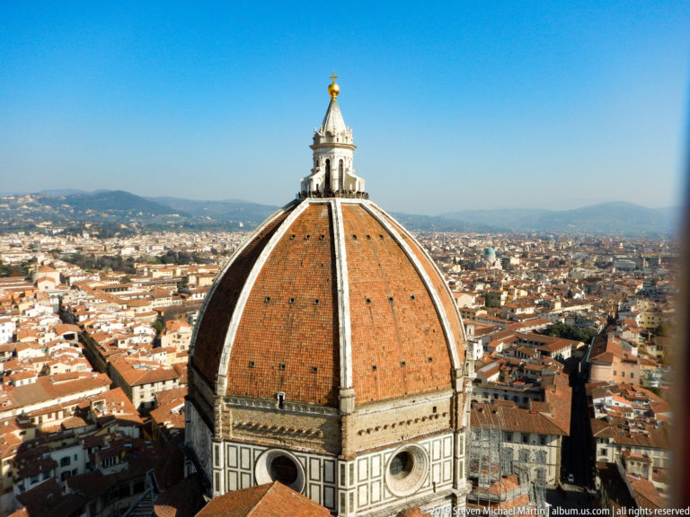 Brunelleschi’s large terracotta dome and lantern rising above the dense rooftops and distant hills of Florence.