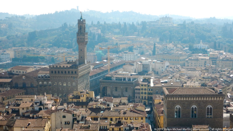 Elevated city view centered on Palazzo Vecchio and the Torre di Arnolfo, with the Loggia dei Lanzi beside Piazza della Signoria.