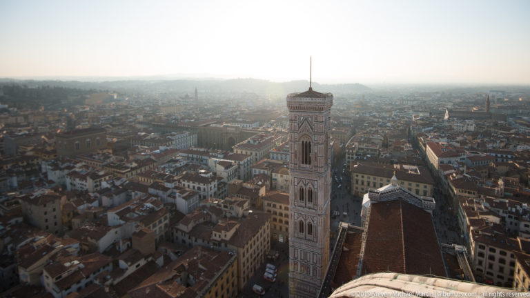 Giotto’s Campanile beside the cathedral roof, viewed from the dome above a hazy expanse of Florence rooftops.