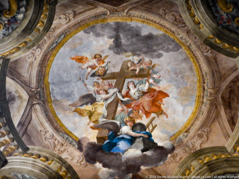 Oval ceiling fresco with central cross, angels, clouds, and seated female figure in blue.