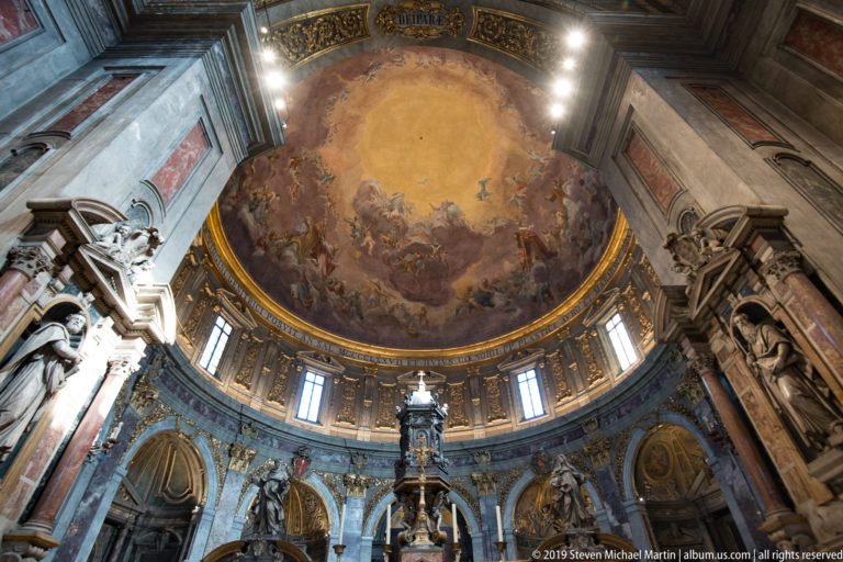 Frescoed dome above drum windows, colored marble, monumental sculptures, and arched openings.