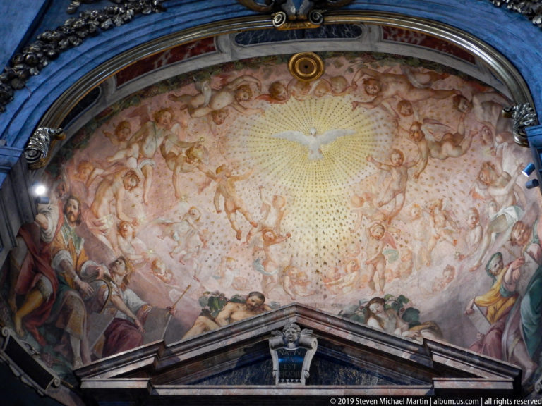 Curved fresco with a radiant dove at center, surrounded by clouds, angels, and gathered sacred figures.