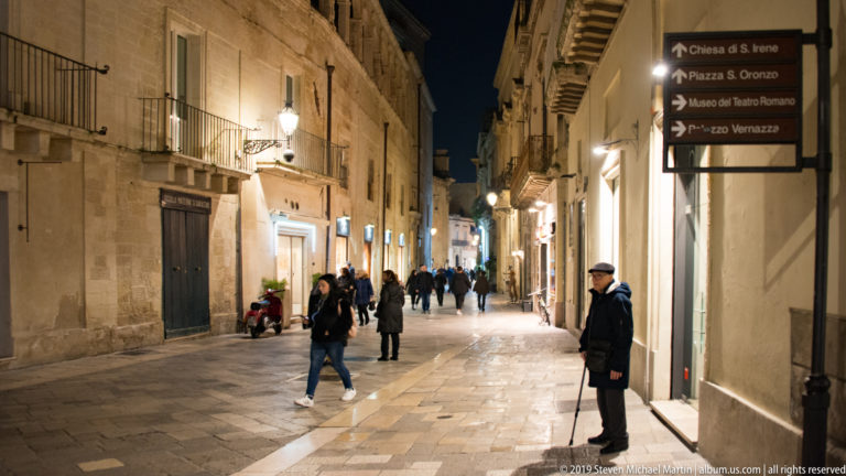 Lecce street signs directing pedestrians to Chiesa di S. Irene, Piazza S. Oronzo, and Museo del Teatro Romano at night.