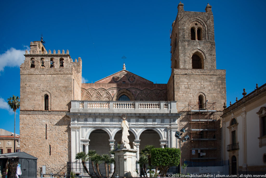 The cathedral’s west façade, with two square towers above an arcaded entrance portico and the plaza in front.