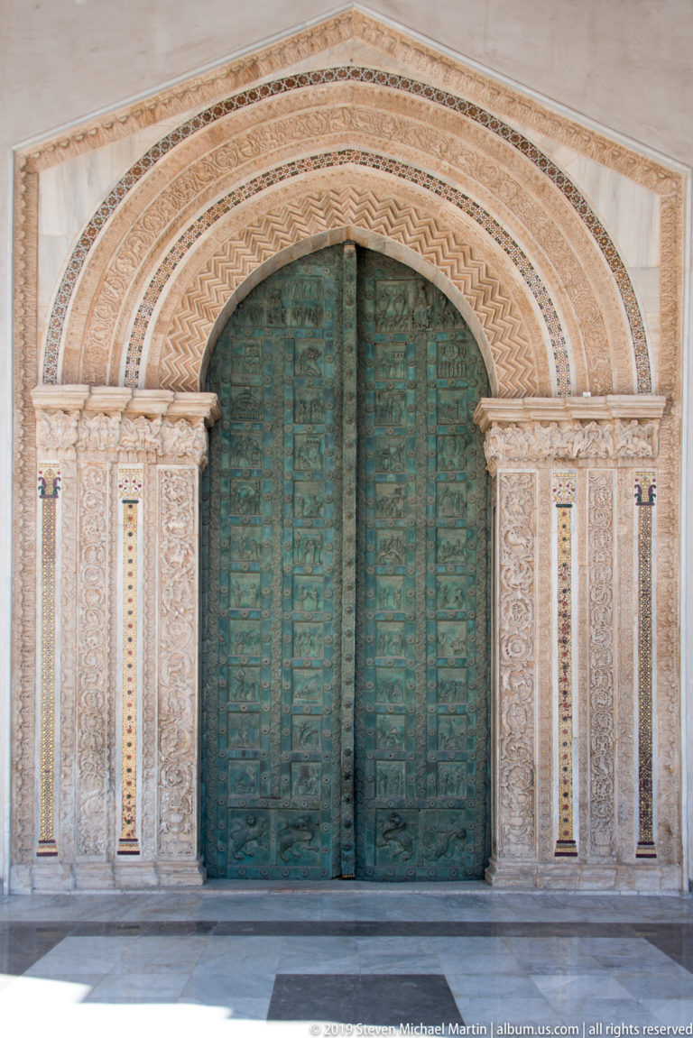 Bonanno Pisano’s bronze Gates of Paradise fill the cathedral entrance, their many relief panels set within a patterned stone arch.