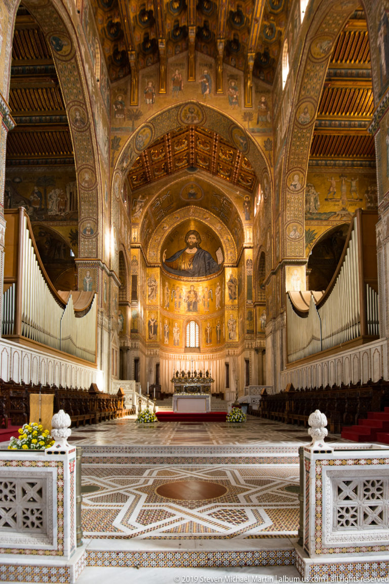 A patterned marble nave ends at an altar beneath a gold mosaic apse.