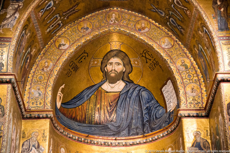 Close detail of Christ Pantocrator’s face, halo, blessing hand, and open book in the apse mosaic.