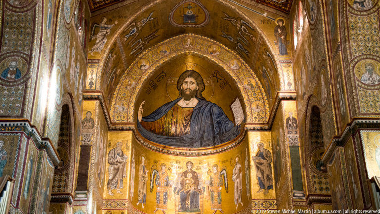 Christ raises a hand and holds an open book within a gold mosaic framed by smaller figures.