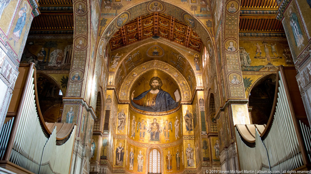 A monumental Christ mosaic fills the apse above the sanctuary, framed by tall decorated walls.