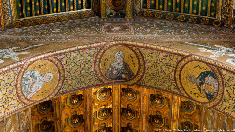 Christ raises a hand and holds an open book, surrounded by smaller saint medallions.
