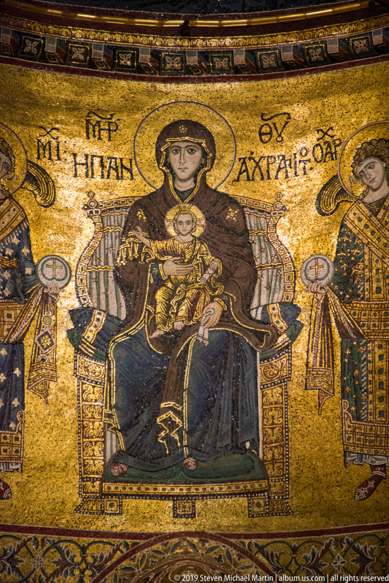The Virgin Mary holds the haloed Christ Child between two standing attendants.
