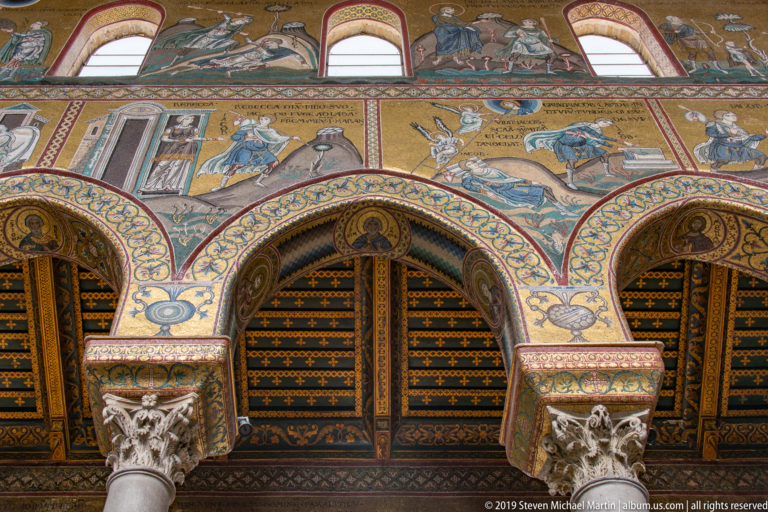 Two pale carved marble furnishings stand before the gold mosaic apse and sanctuary.