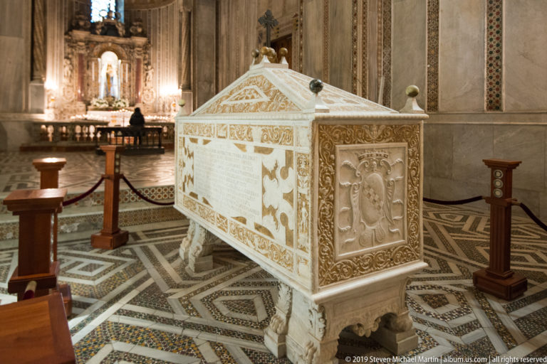 A long patterned nave leads to an altar beneath a towering gold mosaic apse.