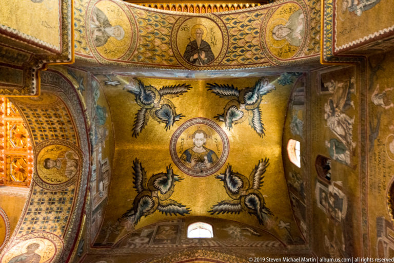 A small haloed figure sits above a central mosaic medallion framed by paired winged creatures.